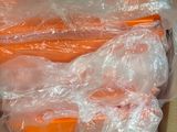 several carrots wrapped in plastic sitting on top of a cardboard box