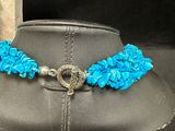 blue flower necklace with a silver clasp on a black mannequin