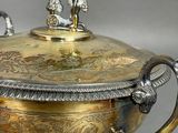 a silver and gold bowl with a figurine on top of it