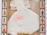 poupée vêtue d'une robe blanche avec un nœud rose, dans une boîte
