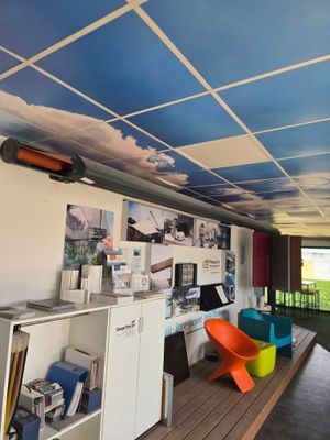 une pièce avec un bureau, des étagères, des chaises et des images au plafond