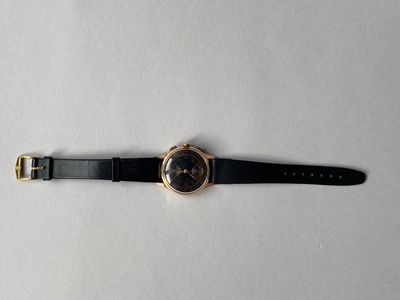 gros plan d'une montre sur une surface blanche avec un bracelet noir