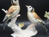 deux figurines représentant des oiseaux perchés sur une branche d'arbre