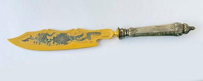 an image of a knife with a gold handle on a white surface