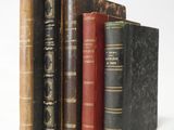 several old books are stacked on top of each other on a white surface