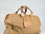 the large duffel bag is tan and has a tan leather handle