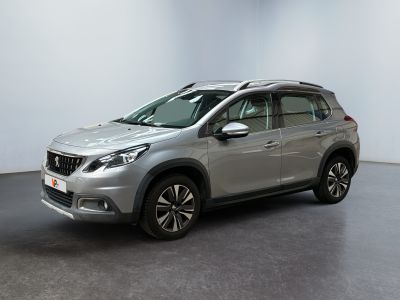La voiture argentée est garée dans une pièce blanche au sol noir.