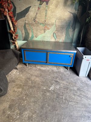 a blue chest of drawers in a room with a painting on the wall
