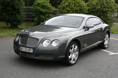 La Bentley est garée sur le parking, près des arbres.
