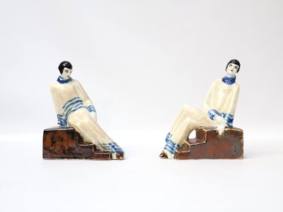 pair of ceramic figurines of a man and a woman sitting on blocks