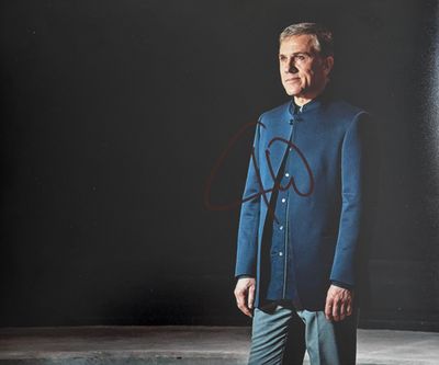 une vieille photo d'un homme en costume bleu, debout devant un mur noir