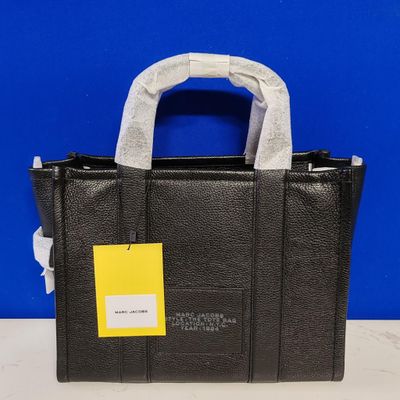 a close up of a black handbag with a yellow tag on it