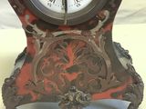 a red and black clock with roman numerals on it