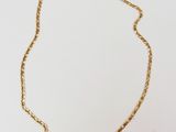 gros plan d'un collier à chaîne en or sur une surface blanche