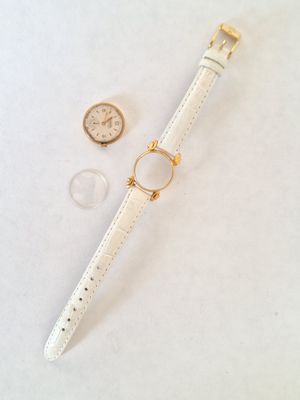 the watch is laying on a white surface next to a coin