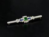 a close up of a diamond and emerald hair clip