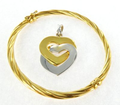 a close up of a gold and silver heart pendant on a wire