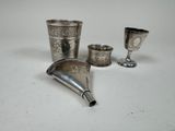 trois tasses en argent et un entonnoir en argent posés sur un plateau blanc