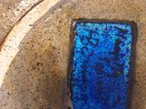 un verre bleu posé sur une assiette, par terre