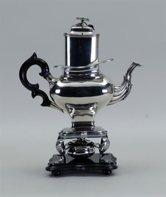 théière plaquée argent avec une anse noire, posée sur un socle