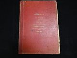 an old red book sitting on top of a black table