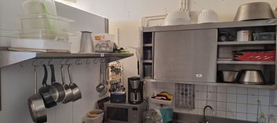 une cuisine avec des placards en inox et des casseroles et poêles accrochées au mur