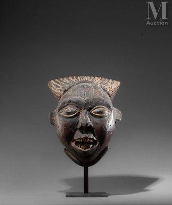 a close up of a wooden mask on a stand on a gray surface