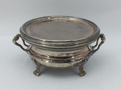 une assiette en argent ancienne avec des poignées et des poignées sur un support