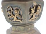 a metal vase with carvings on it sitting on a table