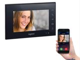 une personne tenant un smartphone devant un interphone vidéo