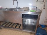 un évier en inox dans une cuisine sale, à côté d'une poubelle