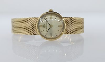 gros plan d'une montre-bracelet en or sur une surface blanche