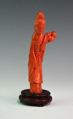 une statue orange représentant un homme tenant un oiseau, posée sur un socle en bois