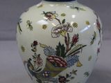a white vase with a bird and flowers on it