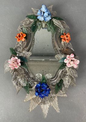 un petit miroir orné de fleurs, posé sur une table