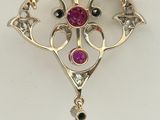 un gros plan sur un collier en or orné d'un pendentif en pierre rose