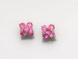 une paire de boucles d'oreilles en saphir rose posées sur une surface blanche