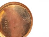 a close up of a gold pocket watch on a white surface