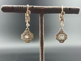 a pair of silver and gold earrings on a branch