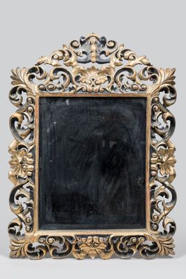 un cadre doré richement décoré, avec un miroir noir au centre