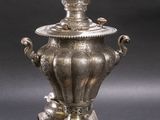 an antique silver plated urn on a stand on a black background
