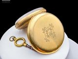 a gold pocket watch sitting on top of a white plate