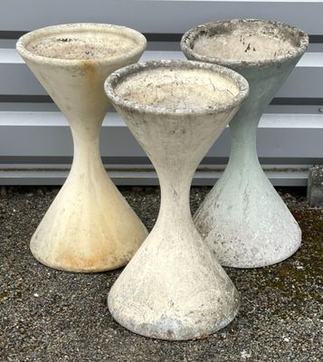 trois vases en ciment posés les uns à côté des autres par terre