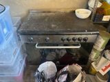 a stove that is sitting in a kitchen with a lot of clutter