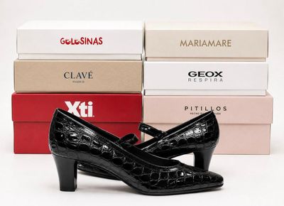 a pair of black shoes sitting on top of a stack of boxes