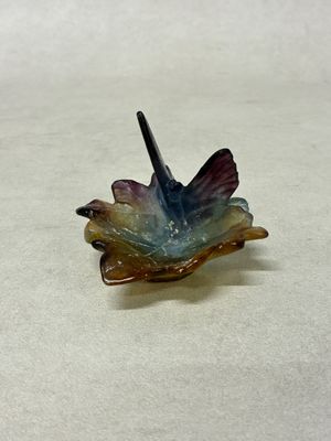 un petit oiseau en verre posé sur une feuille