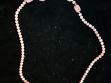 a pink beaded necklace with a heart charm