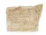 un vieux bloc de pierre portant une inscription sur une surface blanche