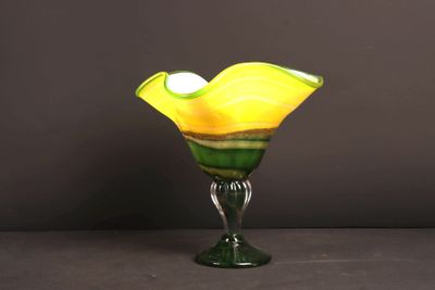a glass vase with a yellow and green flower inside of it
