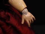 a close up of a doll wearing a red dress and a bracelet